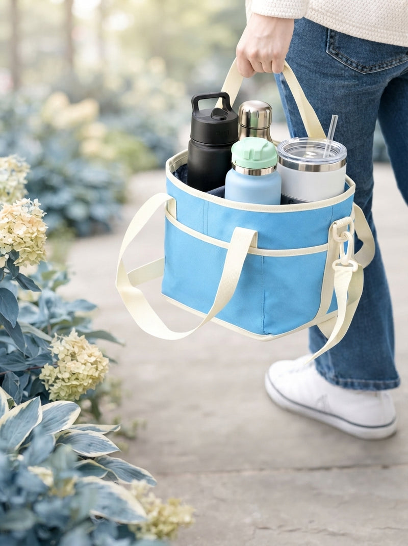 A person carrying a 4-cup drink carrier in an outdoor park setting with a softly blurred background.